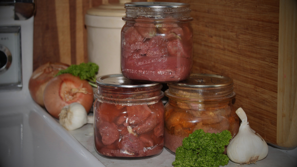 mason jars filled with wild game and on a kitchen counter