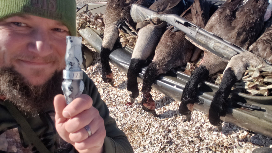Goose hunter, Mike Wec holding a Slayer Honker Slayer goose call next to a pickup truck with harvested geese.