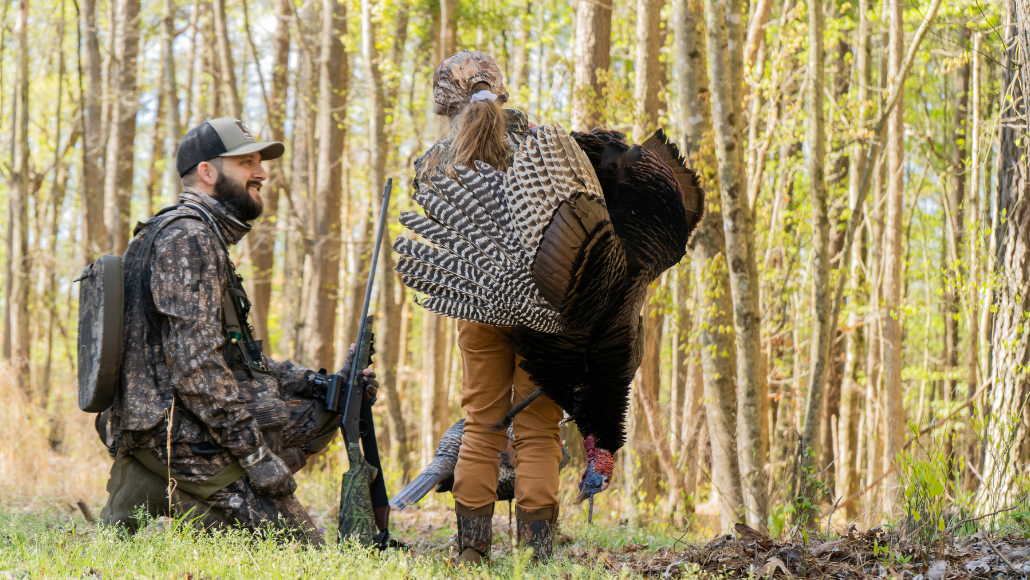 Turkey hunter in the field with daughter and harvested wild turkey