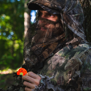 Person in full camouflage gear holding the Center Cut Triple reed - a Ghost Cut diaphragm - from Slayer Calls.