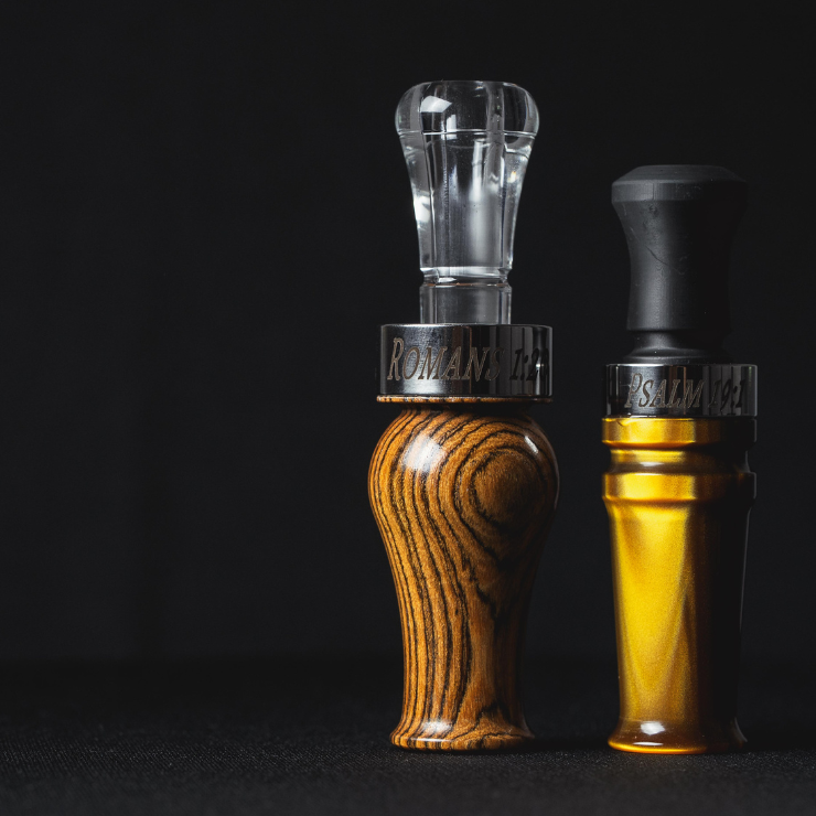 The Suzie Slayer duck call pictured next to the Yolo Bypass hybrid duck call—both engraved with Bible verses. Custom duck calls make the perfect gift.