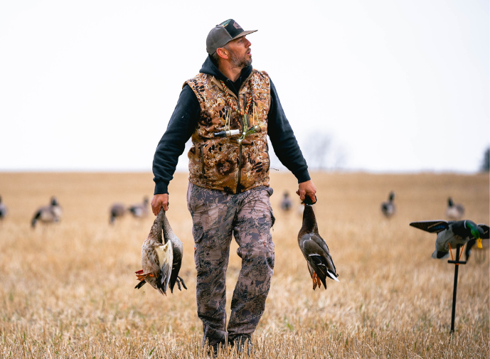 Hunter with ducks in field