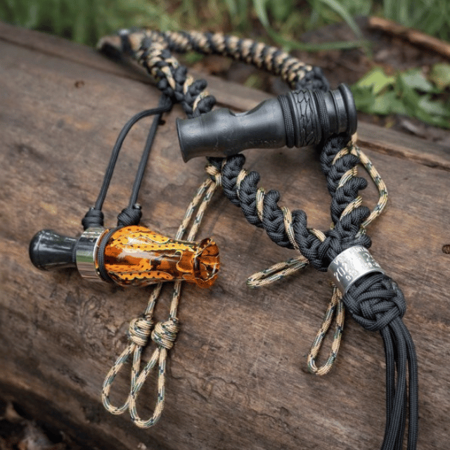 Close up of the FieldPRO Lanyard from Slayer Calls holding the Whistler's Mother duck whistle and the DUBAR duck call.