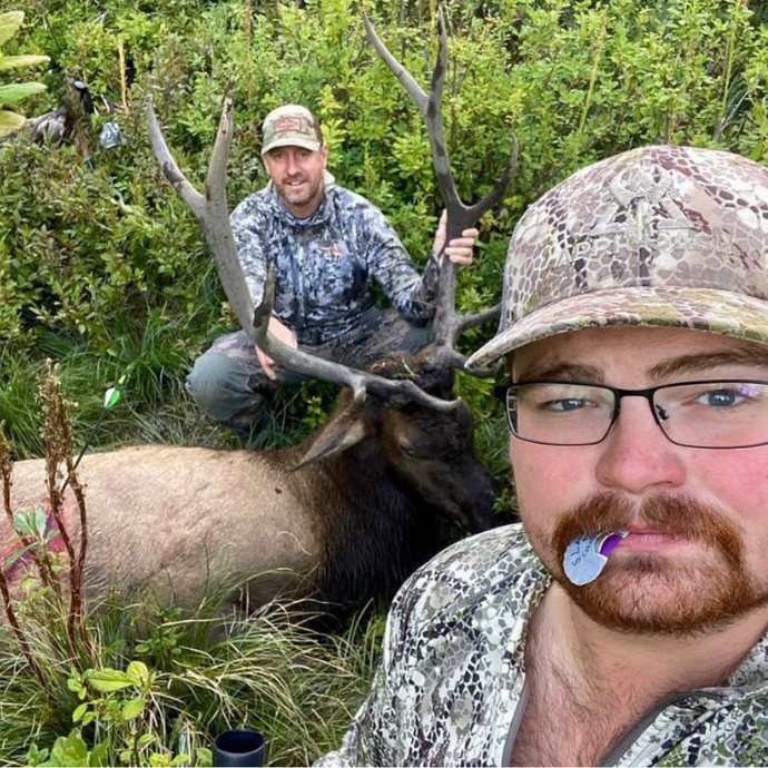 Hunter posing with bull elk after a successful call using Slayer’s Clearwater elk reeds