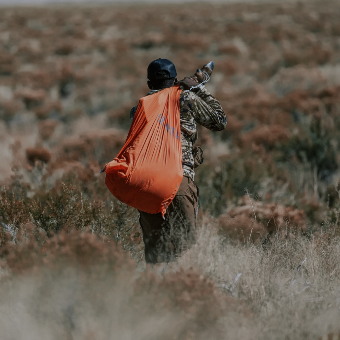 Elk hunter using one of Slayer's bright orange game bags to pack out elk quarter after a successful hunt in the Colorado high desert.