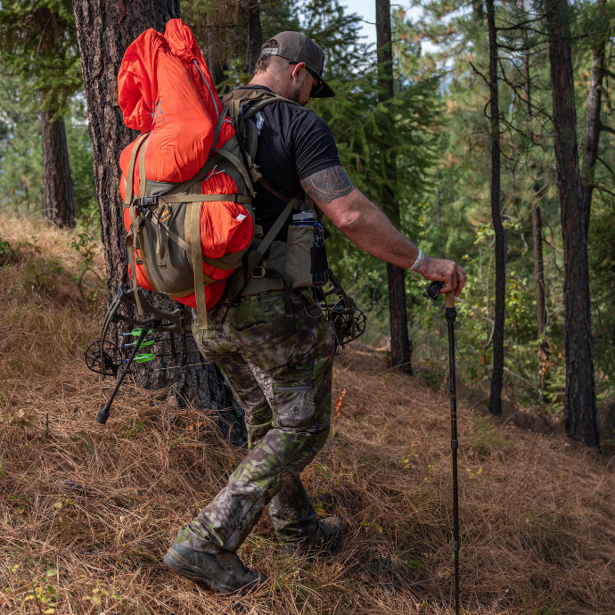 Elk hunter packing out after a successful hunt with orange Slayer game bags shown on his pack