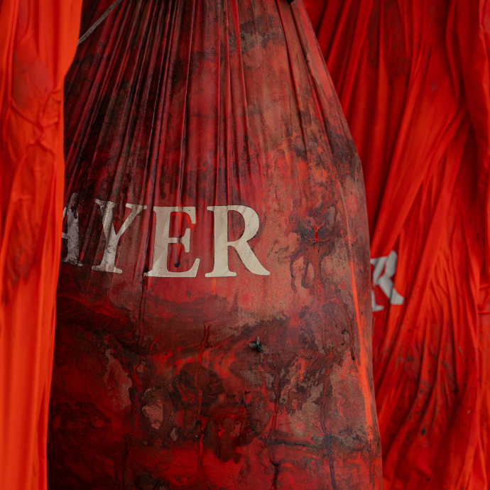 Close up of Slayer orange game bags packed with meat from a freshly harvested bull elk hanging from a tree.