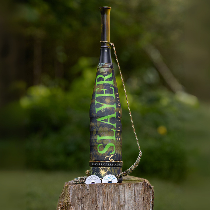 Slayer Calls' ArchAngel bugle tube with Kryptek sleeve, Northfork and Maniac elk reeds posed on a tree stump.