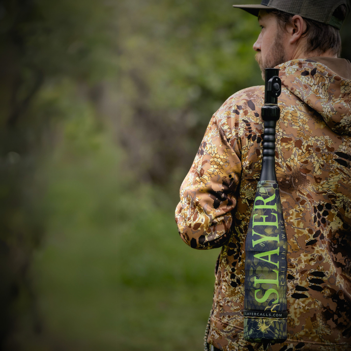 Elk hunter shown with the Enchantress cow call + Swagger elk bugle tube in Kryptek Altitude camo cover, held over his shoulder with paracord bugle tube strap.