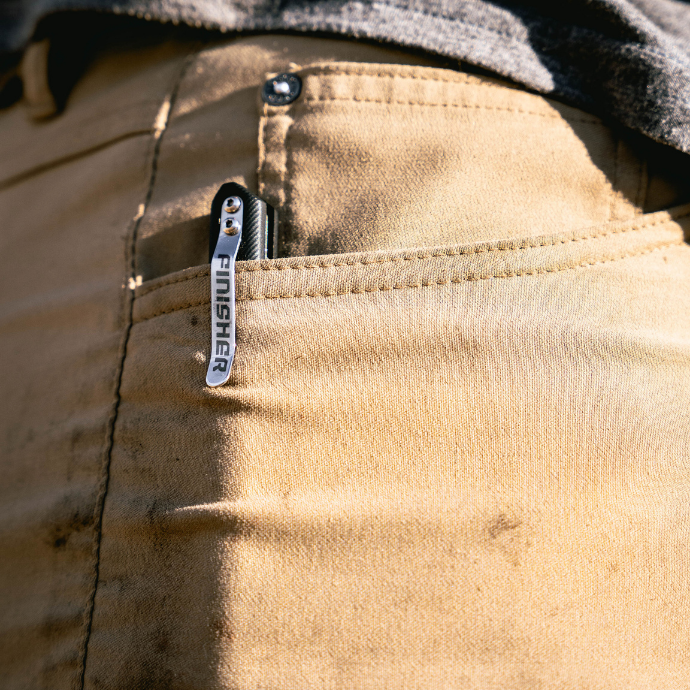 Close-up of a field dressing tool clipped to a hunter’s front pants pocket — compact, field-ready device designed for quick dispatch in waterfowl hunting.