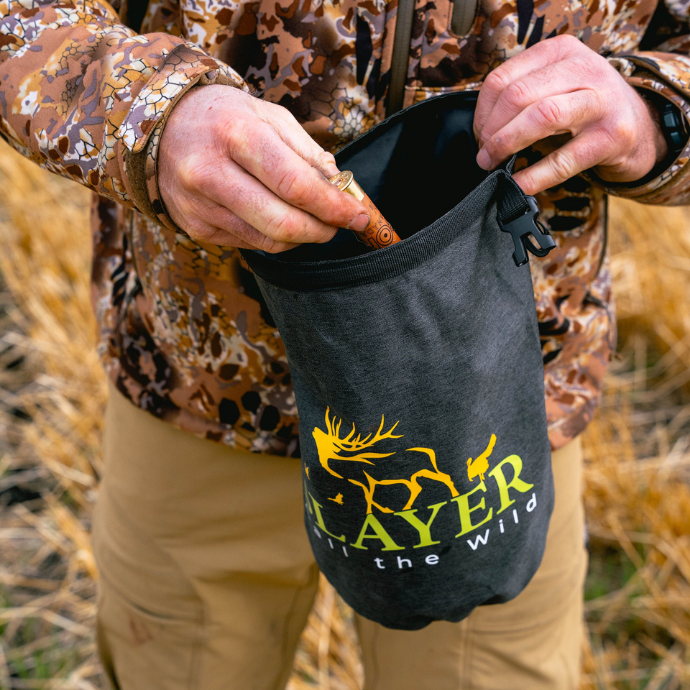Hunter placing gear into a black Slayer dry bag with SLAYER logo — essential water-resistant gear for duck and goose hunting in wet field conditions.