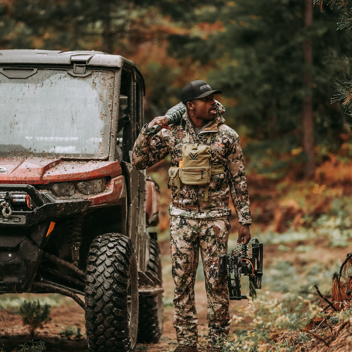 Elk Hunter Darryl Moore, dressed in camo walking away from a red Can-Am, using the Isabella Creek Elk Reed from the Clearwater Diaphragm Series and ArchAngel bugle tube.
