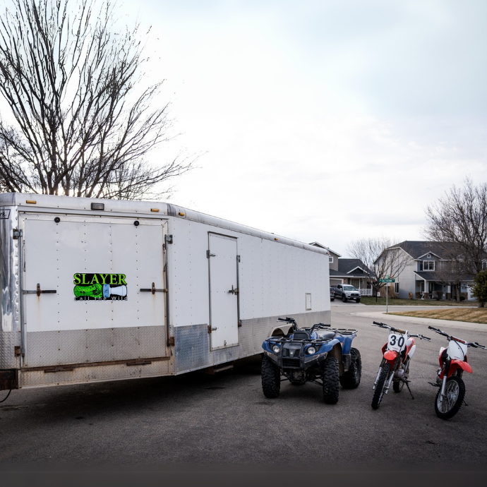 Illustrated Slayer Calls trailer decal featuring a green duck call with tally marks and bold vertical “SLAYER” text, alongside the brand’s slogan “Call the Wild.” Pictured on white trailer.