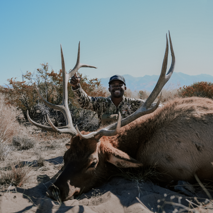 Elk hunter, Darryl Moore kneeling behind a mature bull in Colorado