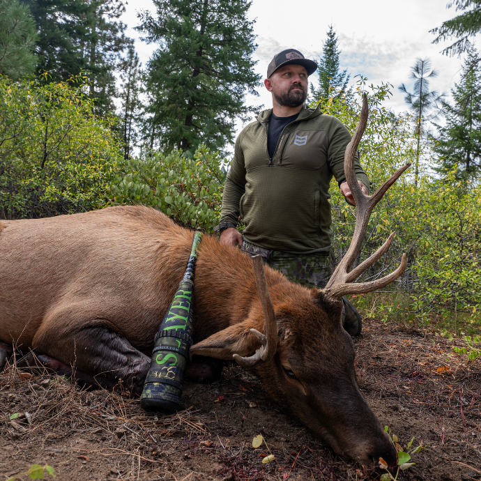 Successful elk hunt using Slayer Calls' Clrearwater Series Elk Reeds and ArchAngel bugle tube — Cody McCarthy poses with mature bull elk in mountain wilderness.