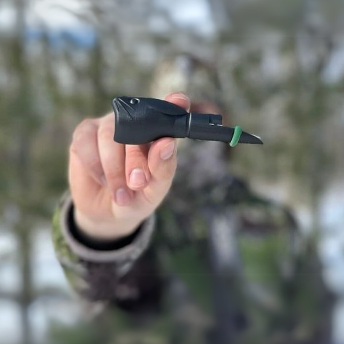Hunter holding up the Wicked Rabbit predator call by Slayer Calls — compact, lightweight open-reed distress call designed to mimic wounded prey and attract coyotes.