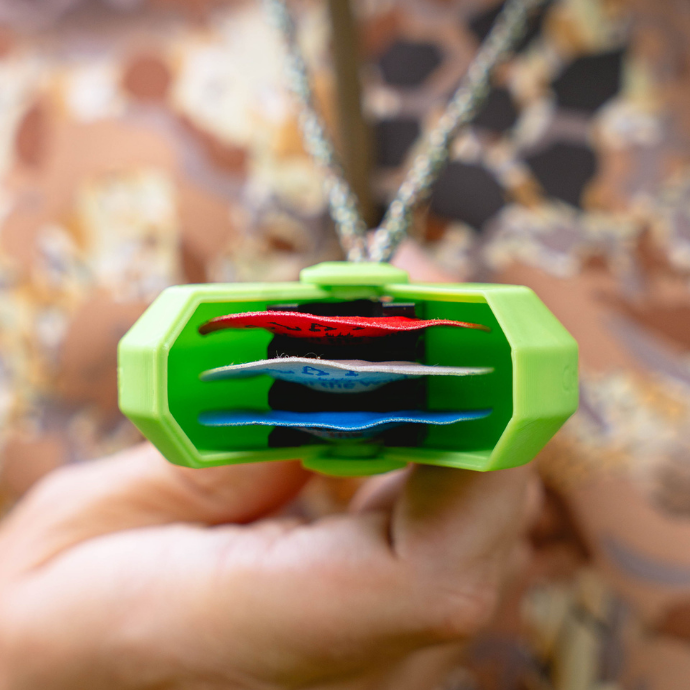 Close up view of an elk hunter holding up Slayer's Reed PAC'r reed holder worn conveniently around his neck for easy access to the Clearwater Series elk reeds stored safely inside.
