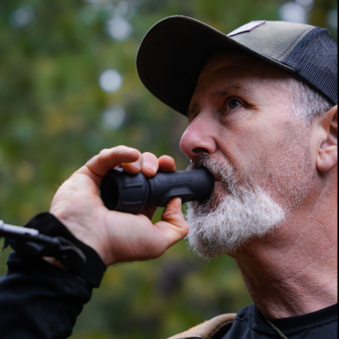 Bill Ayer, Owner and CEO of Slayer Calls blowing into the easy-to-use Enchantress push button cow call.