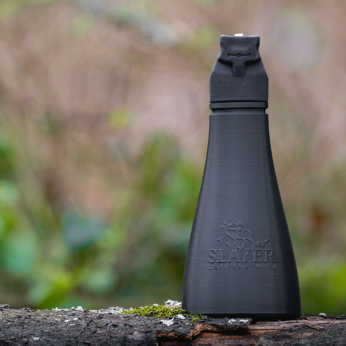 Slayer Calls Gobbler Slayer turkey call standing upright on a mossy log in the woods.