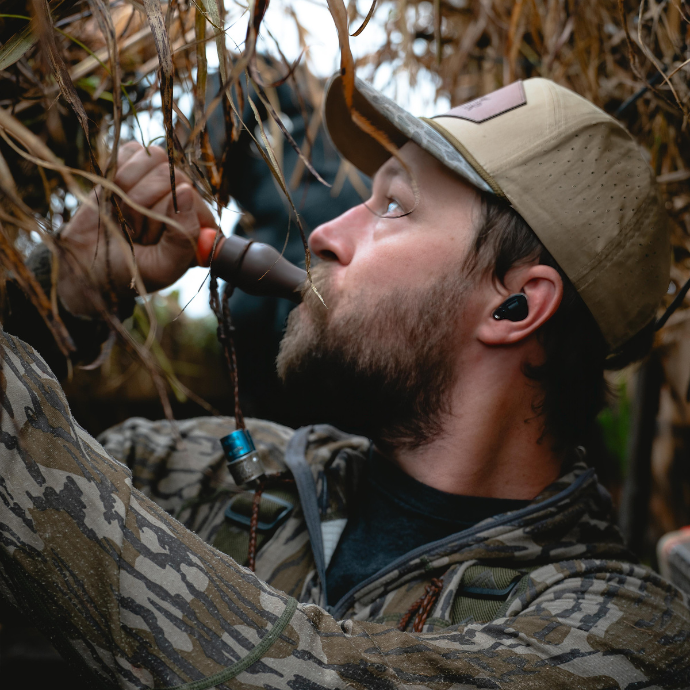 Slayer pro Matt Carey in camouflage clothing and hat using the Rice Wrecker speck call in field blind.