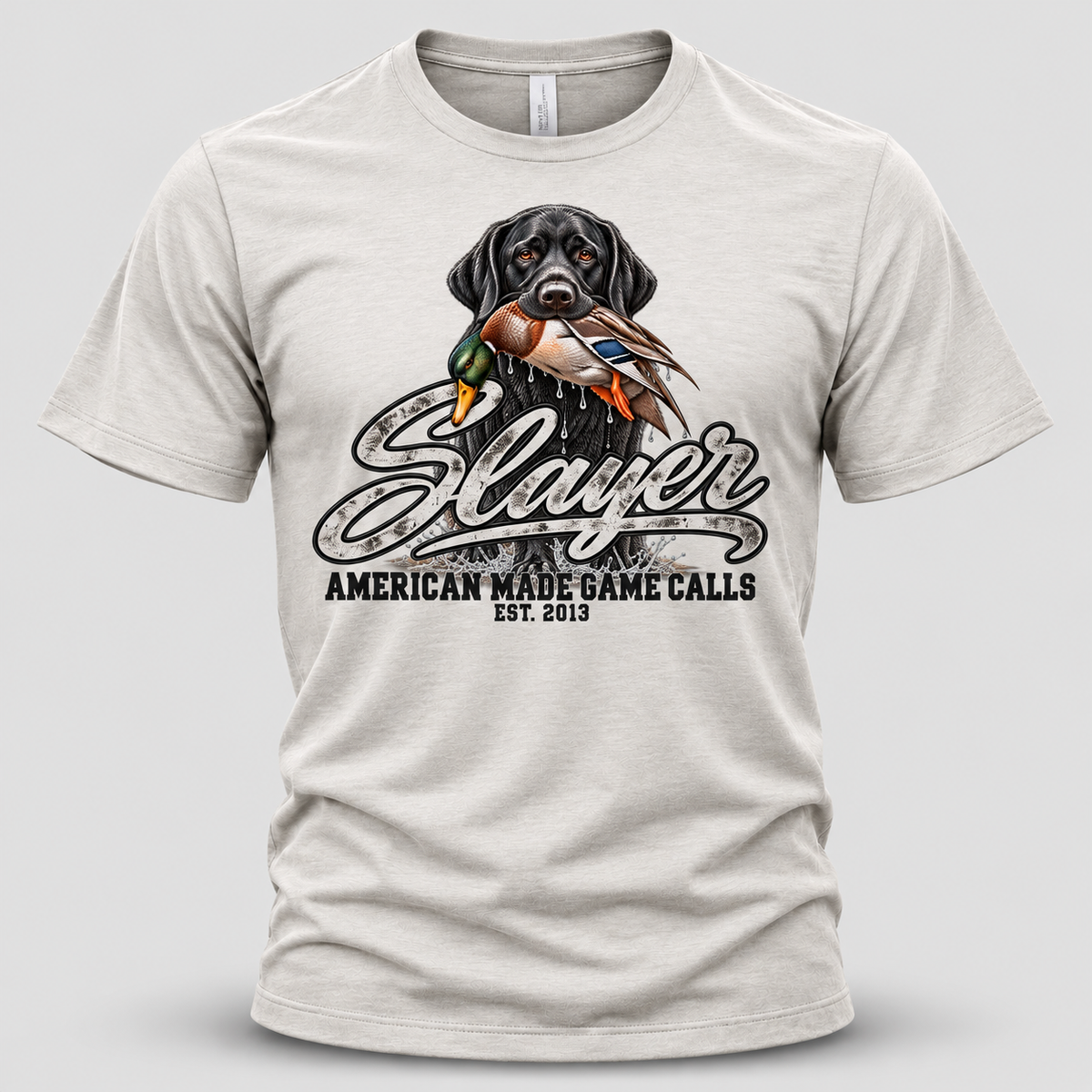 Front view of a white Slayer Calls duck hunting T-shirt featuring a black Labrador retriever holding a mallard duck above the distressed Slayer logo, with American Made Game Calls Est. 2013 lettering.