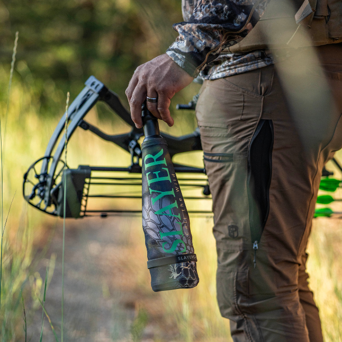 Elk hunter holding a crossbow and a Slayer Lil' Warrior bugle tube in the field.
