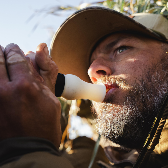 Waterfowl hunter blowing Slayer's Snowstorm snow goose call in a blind