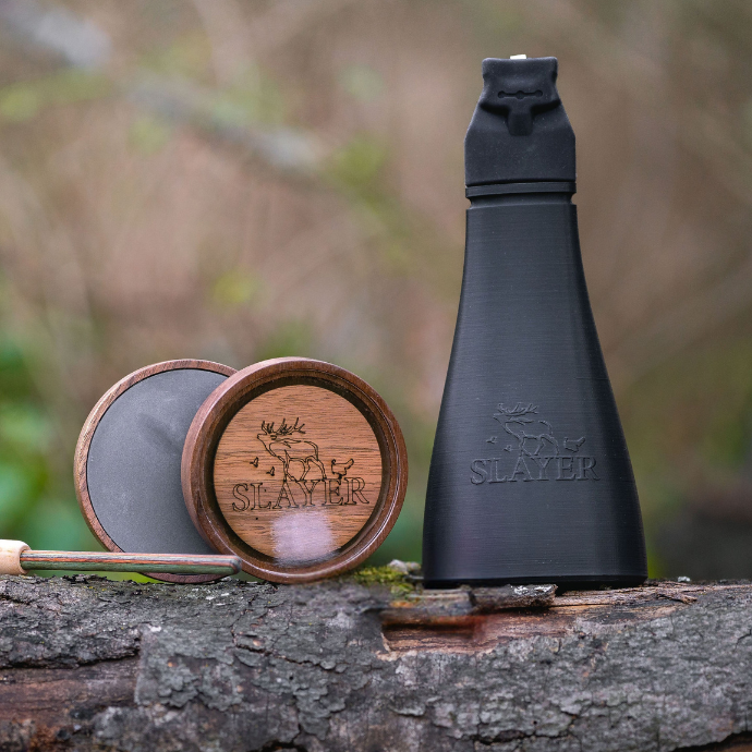 Deadly Duo turkey call set from Slayer Calls featuring the Gobbler Slayer call and Crystal Queen pot call with striker, displayed on a log in the woods.