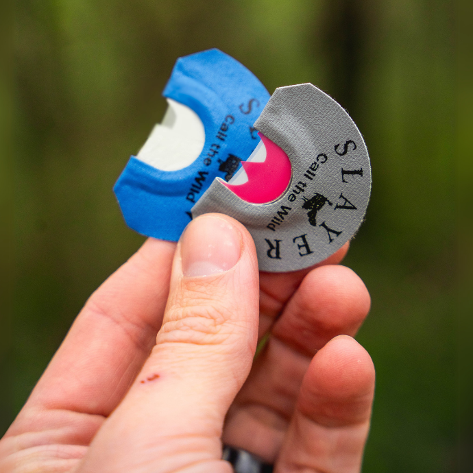 Close-up of a hunter holding Slayer’s Grey Batwing and The Cutter turkey diaphragm calls, featuring precision-cut latex for realistic tones in the field.