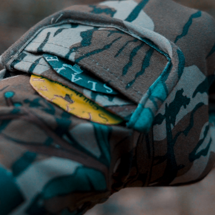 Slayer’s Black Batwing and Snake Bite turkey diaphragm calls tucked into a camo shirt pocket, ready for action in the field.