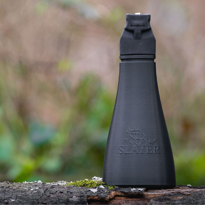 Slayer Calls Gobbler Slayer turkey call standing upright on a mossy log in the woods.