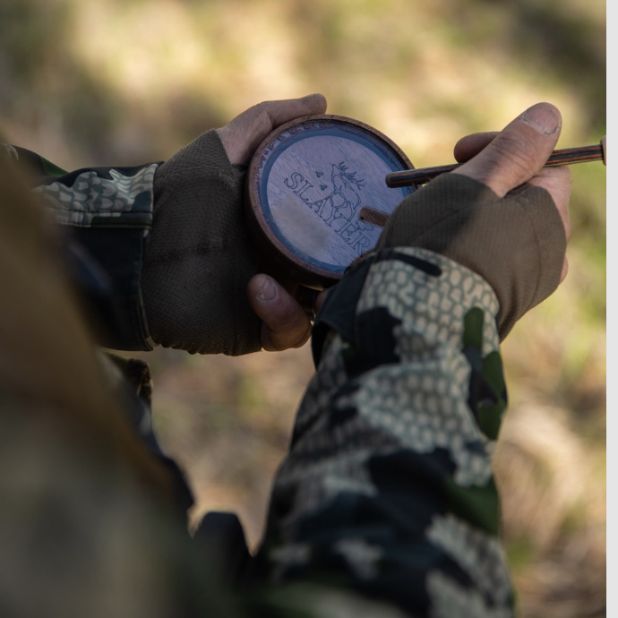 Turkey hunter in camo running the Crystal Queen Pot Call from Slayer Calls