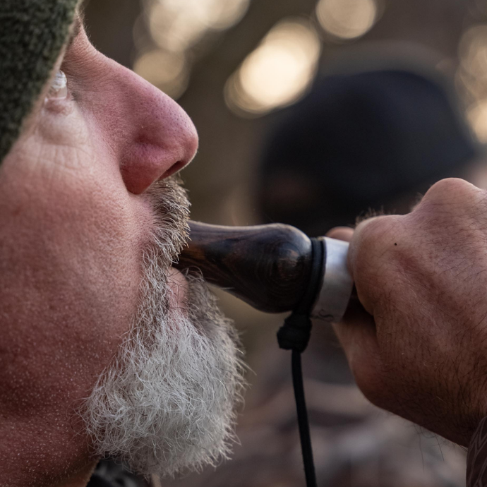 Close-up of a hunter blowing the Suzie Slayer duck call in bocote wood — delivering authentic hen mallard sounds with smooth, responsive tone in the blind.