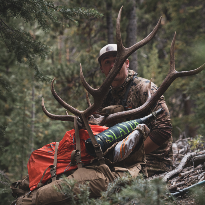 Elk hunter preparing to pack out harvested bull elk through rugged terrain after calling it in with Slayer’s ArchAngel bugle tube and Clearwater reeds.