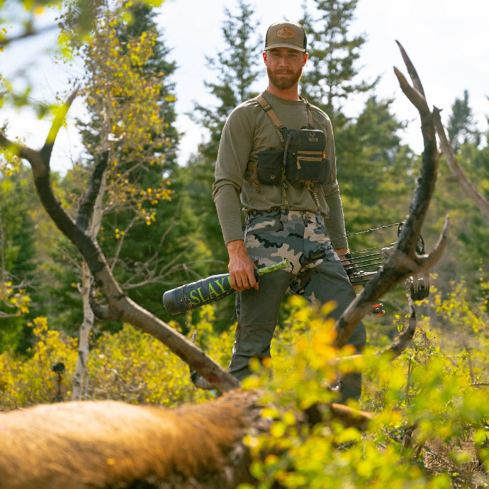 Successful elk hunt using Slayer Calls premium elk reeds and bugle tubes — hunter poses with mature bull elk in mountain wilderness.