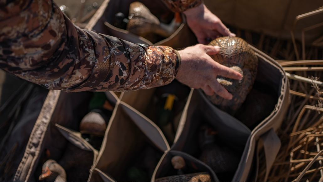 duck hunter reaching into a blind bag filled with duck decoys