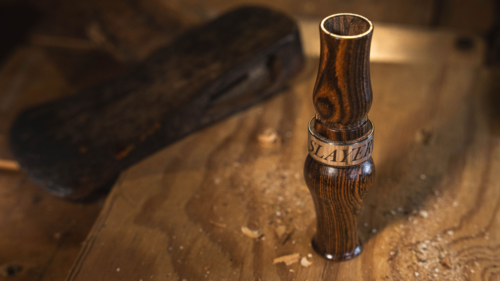 Bocote wood Axe Honker Slayer by Slayer Calls on a wood workbench with wood shavings and an axe nearby