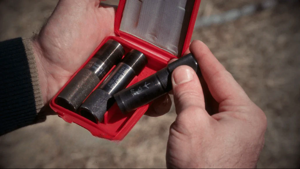 Waterfowl hunter holding a red case with choke tubes in their hand.