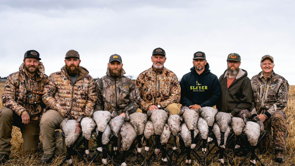 a group of waterfowl hunters posing for a photo with their Canada geese