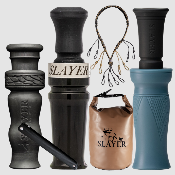 Collection of Slayer duck calls including a black Yolo single reed duck call, 4 in 1 whistle, blue and black Delrin MC duck call, dry bag, paracord lanyard and field dresser on a light gray background.