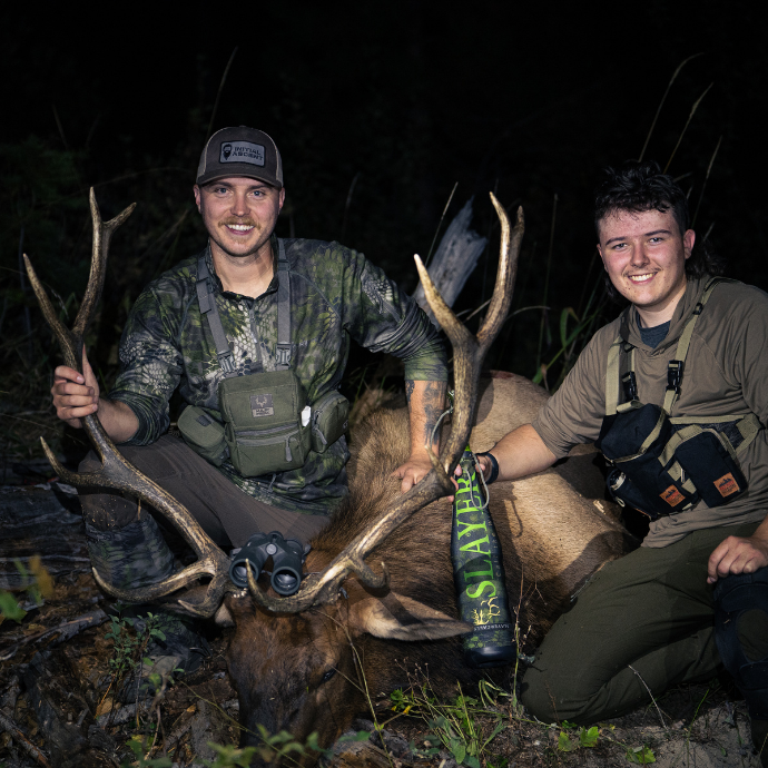 Successful elk hunt using Slayer Calls' Clrearwater Series Elk Reeds and ArchAngel bugle tube — a pair of elk hunters pose with mature bull elk in Idaho mountain wilderness.