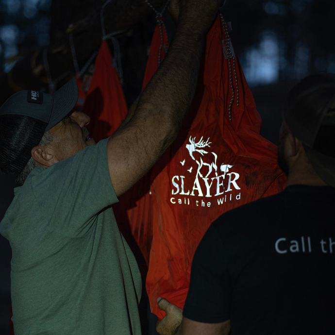 Elk hunters hanging Slayer game bags with freshly harvested elk meat in a tree.