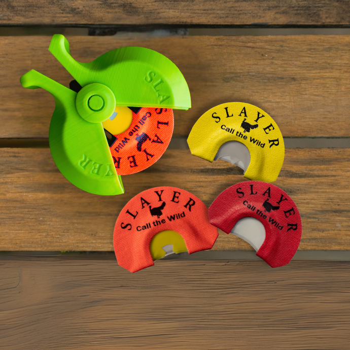 Assortment of Slayer turkey reeds on wooden surface shown with a Slayer green turkey reed holder.