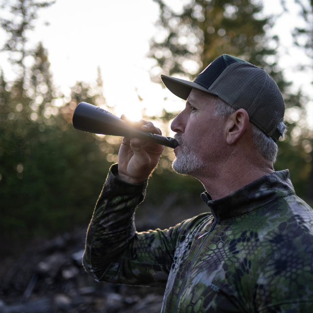 Turkey hunter in the field producing realistic gobbles on Slayer's gobbler slayer turkey call. 