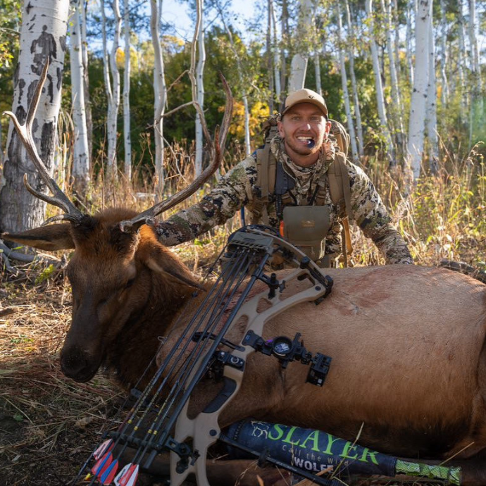Elk hunter poses with mature bull elk called in using Slayer's Logger Elk Reed from the Clearwater Diaphragm Series and ArchAngel bugle tube—successful elk hunting with premium elk calls in the Rocky Mountains.