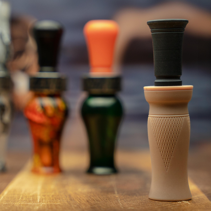 A collage of duck calls — 3 are blurred while the MC duck call is in full focus. 