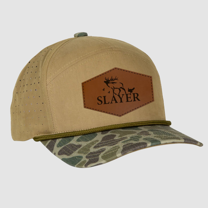 Seven panel beige trucker hat with a camo bill and leather patch with the Slayer logo in black.