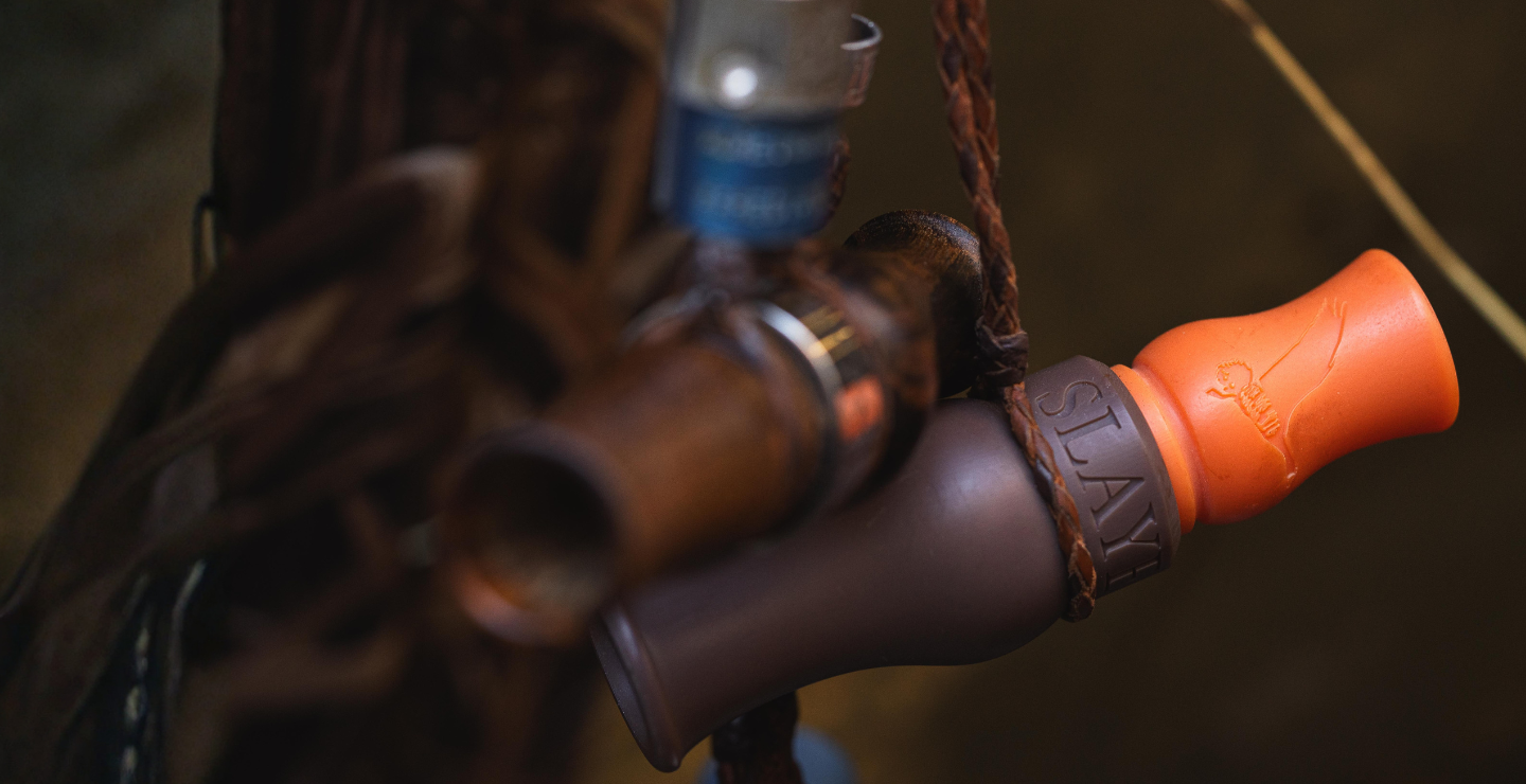 Close up of Slayer's new Rice Wrecker speck call, budget friendly and in the field performance — pictured hanging from lanyard with other waterfowl calls.