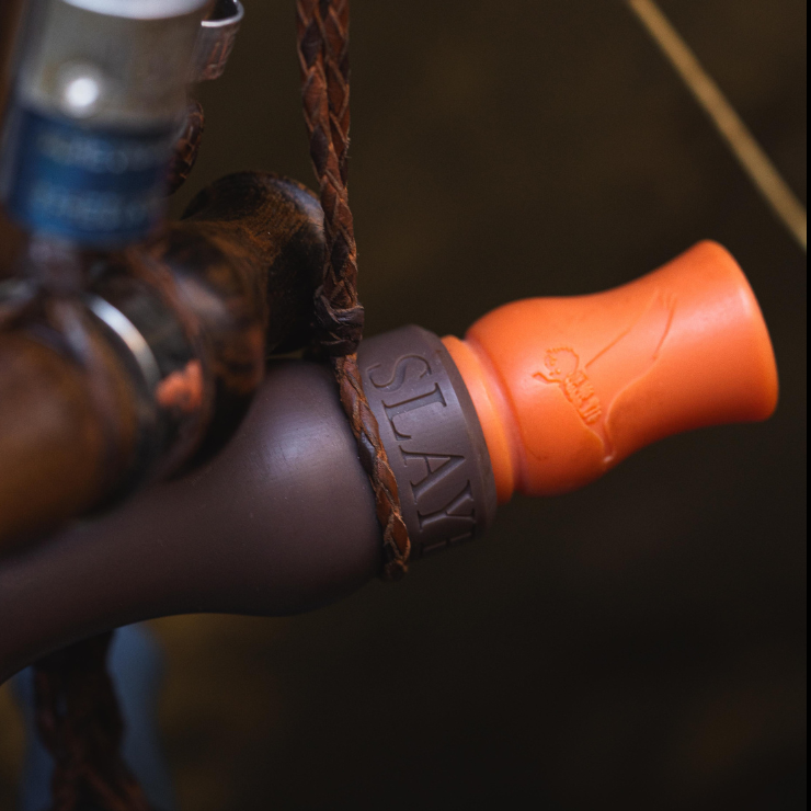 Close up of Slayer's new Rice Wrecker speck call, budget friendly and in the field performance — pictured hanging from lanyard with other waterfowl calls.