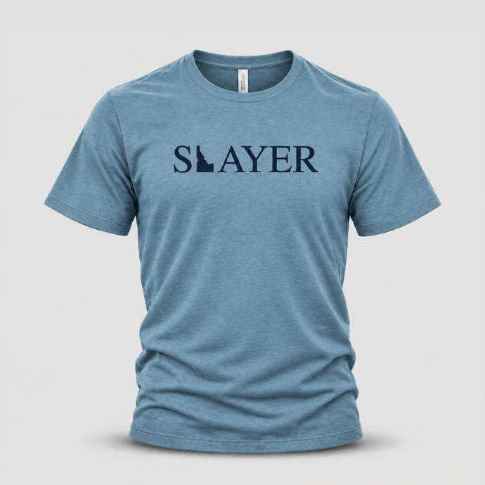 Front view of a blue Slayer Idaho Wild T-shirt with a navy SLAYER wordmark incorporating the Idaho state silhouette.